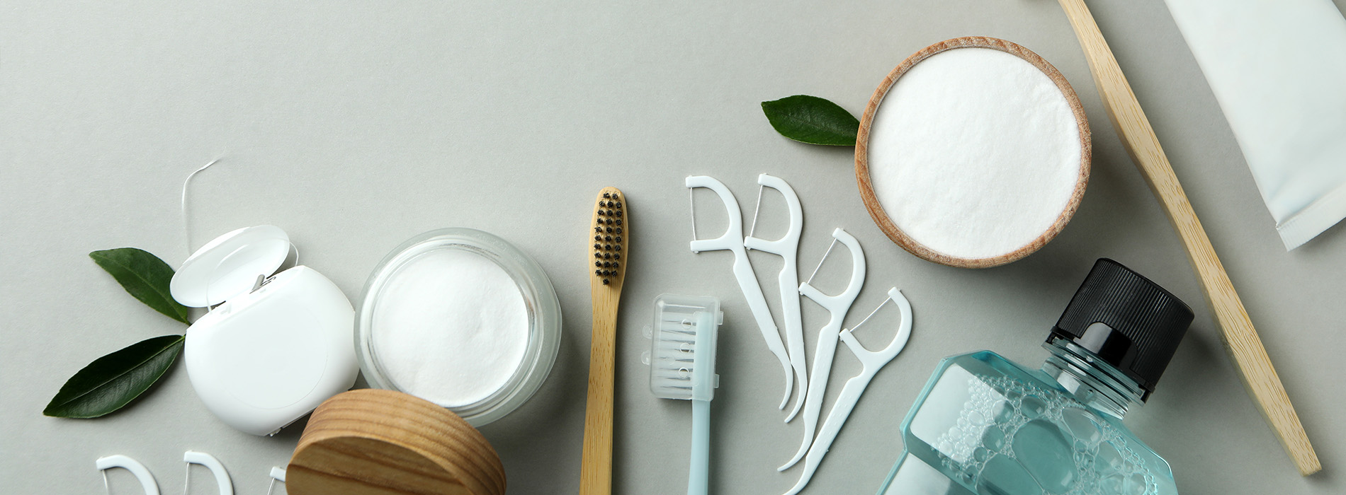 The image shows a collection of skincare products and tools arranged on a surface with a green background.