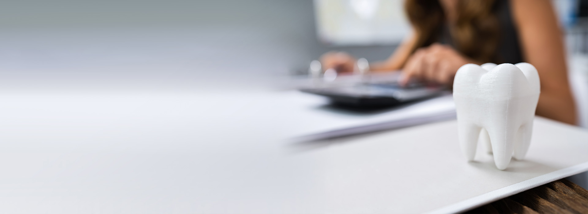 The image shows a person sitting at a desk with a computer mouse, papers, and a toothbrush holder on the desk.