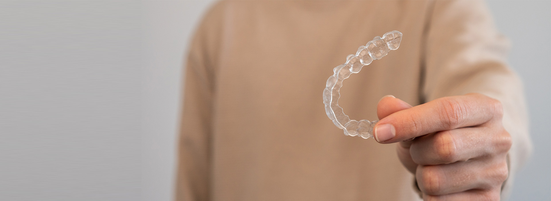 A hand holding a clear bubble with a frosted surface against a blurred background.