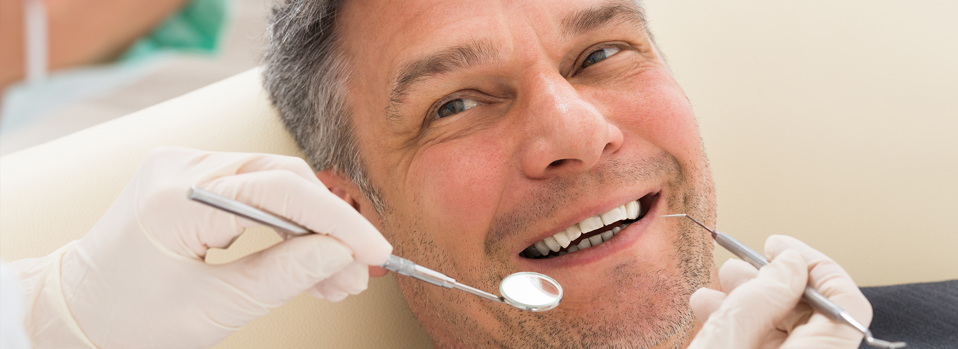 A man receiving dental care with a smile on his face, surrounded by dental tools and professionals.