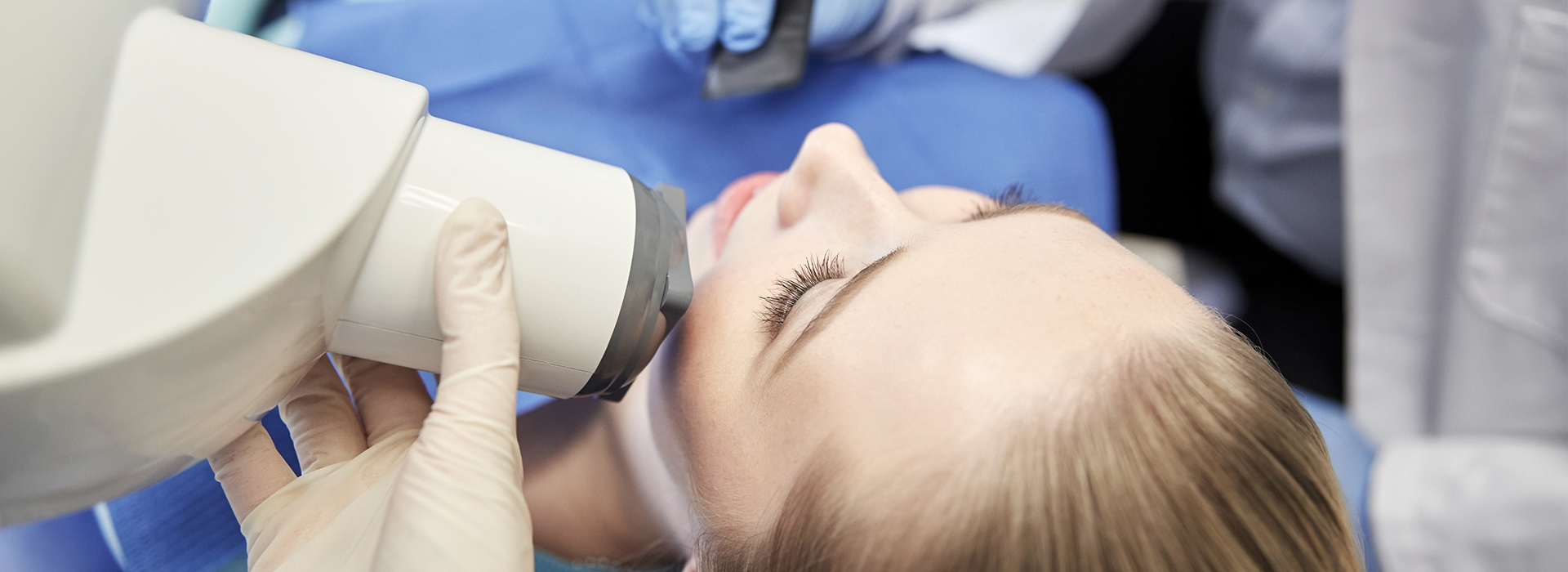 A woman receiving dental treatment with a dentist using a digital scanner.