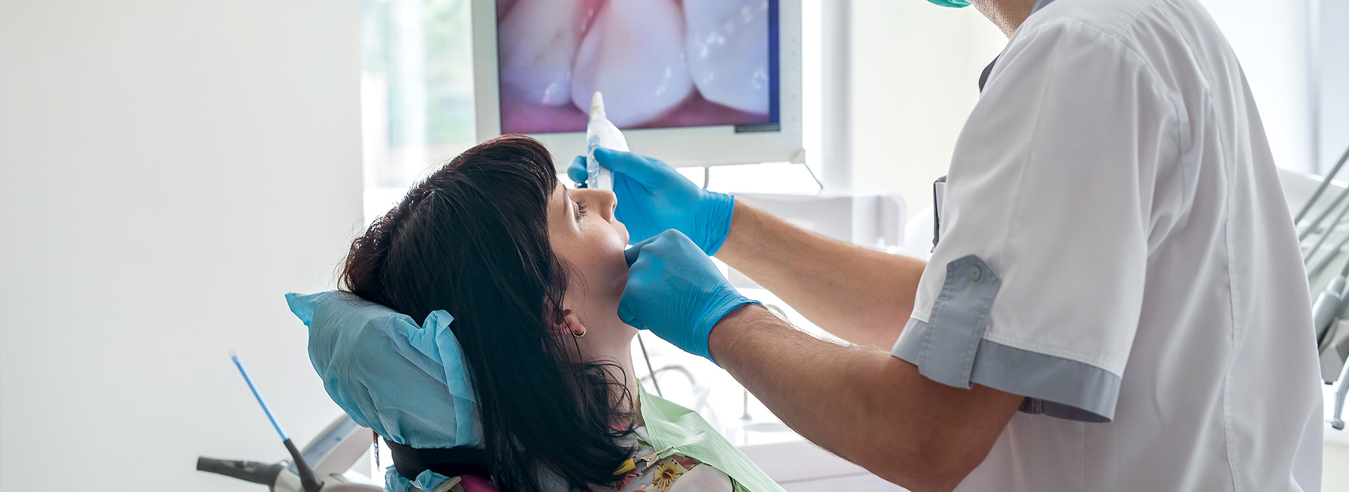 A dental professional performing a procedure on a patient with a blue surgical mask and protective eyewear.