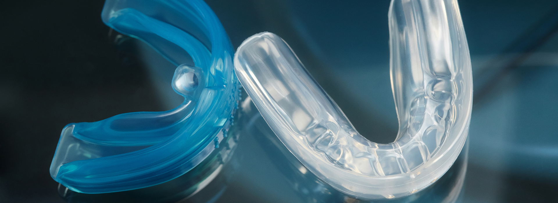 The image shows a clear plastic toothbrush with blue bristles on a transparent surface, next to a close-up of a single blue bristle against a blurred background.