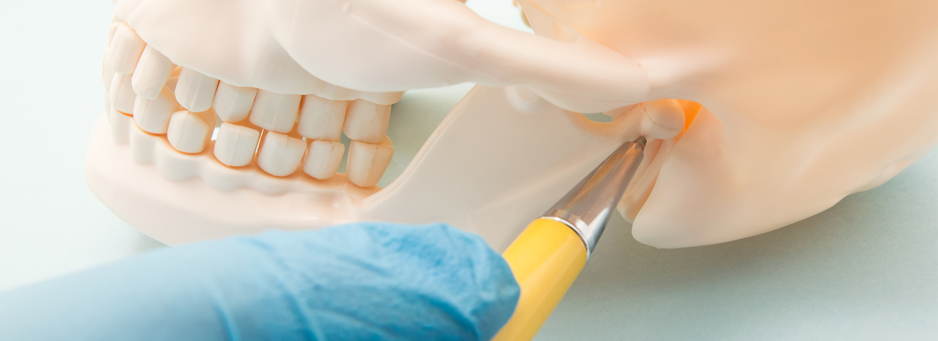 A medical setting with a plastic skull being prepared for dental implants, featuring tools such as a drill and scalpel.