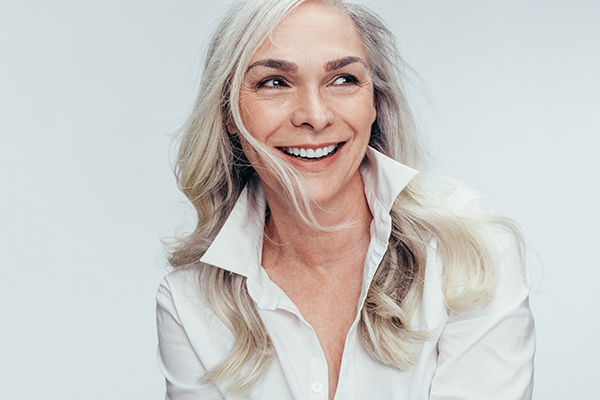 A woman with short blonde hair and a slight smile, wearing a white shirt, poses for a portrait.